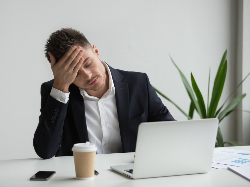 frustrated millennial businessman having strong headache tired from laptop work